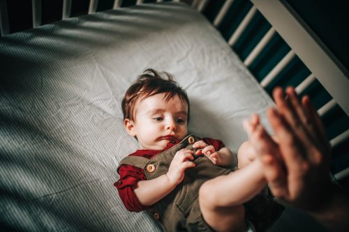 baby in gray shirt lying on bed