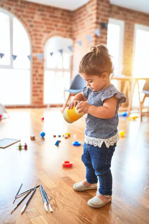 Beautiful toddler holding plastic glass at kindergarten