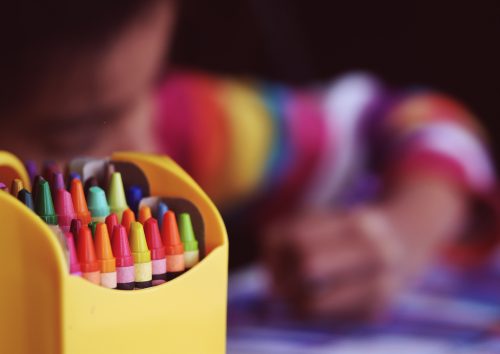 Crayons beside child coloring