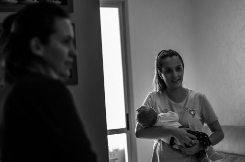 woman in crew neck t-shirt holding baby in grayscale photography