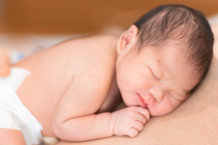 baby sleeping on persons body