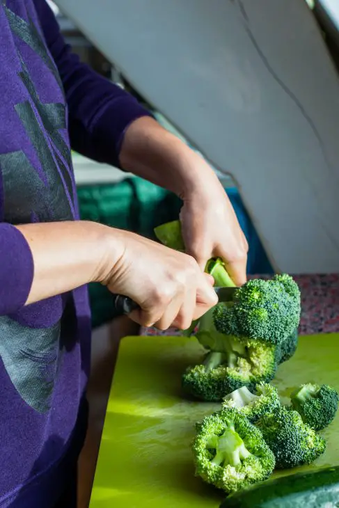 person slicing green broccoli