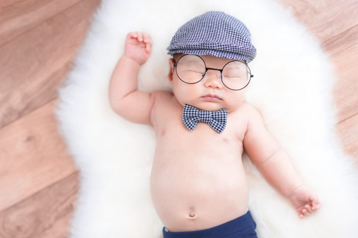 baby with beret lying on white fleece rug